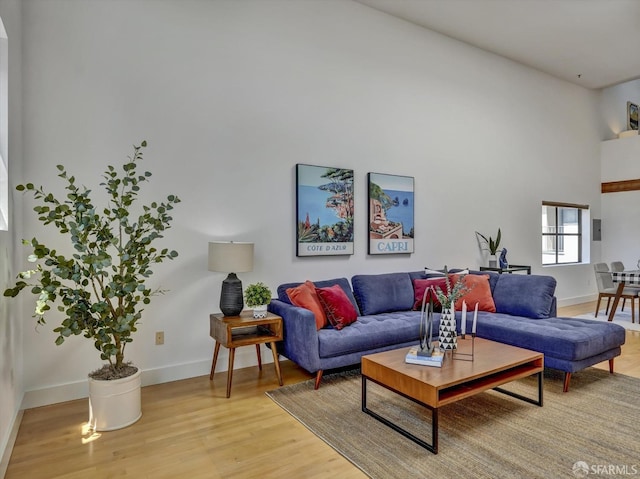 living room featuring light wood-type flooring and a high ceiling