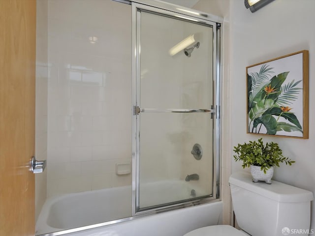 bathroom with combined bath / shower with glass door and toilet