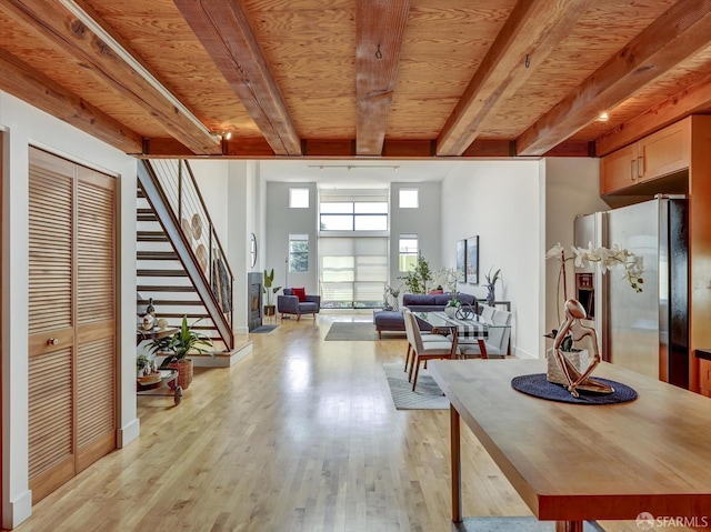 interior space with beamed ceiling, wood ceiling, light hardwood / wood-style floors, and a high ceiling