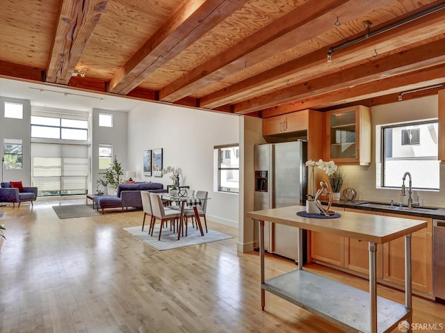 kitchen featuring beamed ceiling, sink, tasteful backsplash, light hardwood / wood-style flooring, and appliances with stainless steel finishes