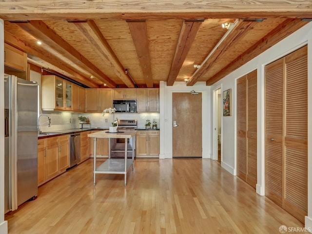 kitchen featuring light wood-type flooring, a center island, beam ceiling, decorative backsplash, and stainless steel appliances