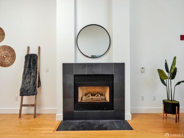 details featuring a tiled fireplace and hardwood / wood-style floors