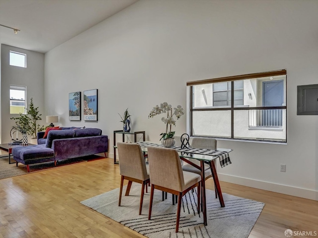 dining area featuring light hardwood / wood-style flooring, a wealth of natural light, and a high ceiling