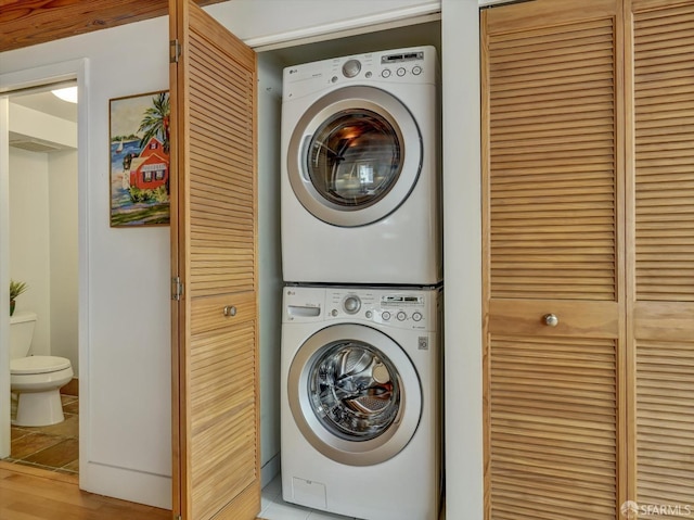 washroom featuring stacked washer / drying machine and light hardwood / wood-style flooring