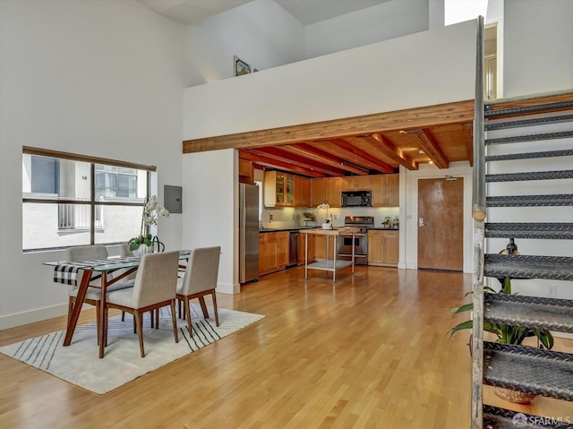 dining area featuring beamed ceiling, light hardwood / wood-style flooring, and high vaulted ceiling