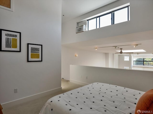 bedroom with light carpet, a high ceiling, and a skylight