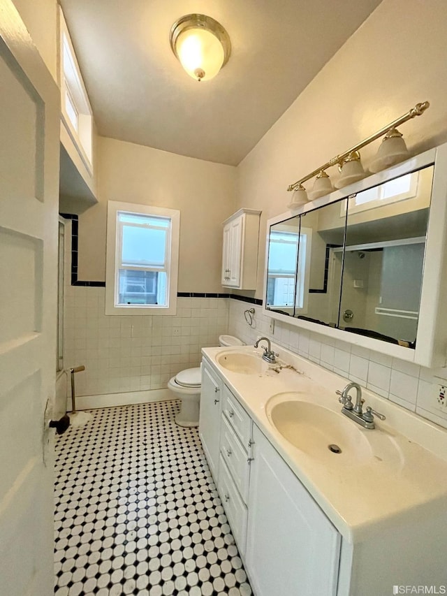 bathroom with vanity, toilet, walk in shower, and tile walls