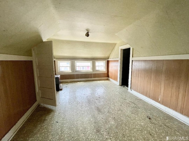 additional living space with vaulted ceiling and wood walls