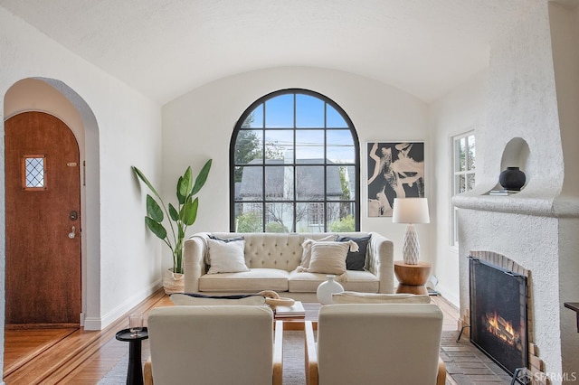 living room featuring vaulted ceiling, a fireplace, and light hardwood / wood-style flooring