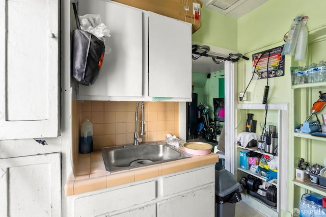 kitchen featuring white cabinets, backsplash, tile counters, and sink