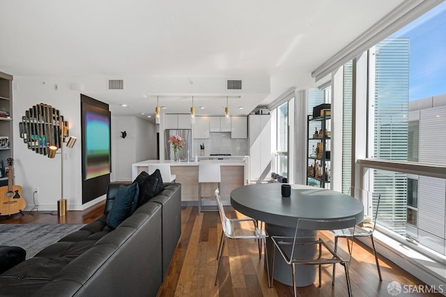 living area with floor to ceiling windows, visible vents, and dark wood-type flooring