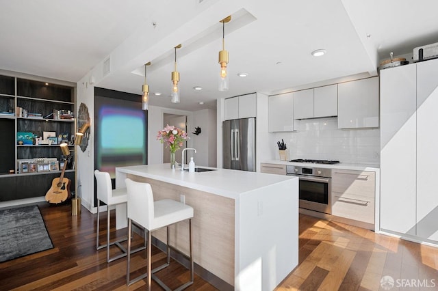 kitchen featuring stainless steel appliances, wood finished floors, a sink, white cabinetry, and modern cabinets