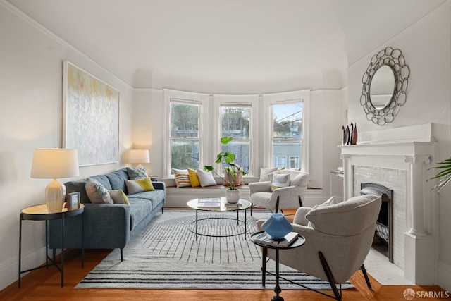 living area with a brick fireplace and wood finished floors