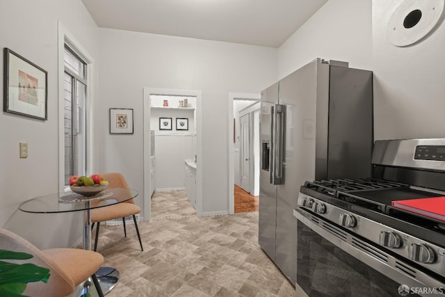 kitchen with stainless steel range with gas stovetop and baseboards