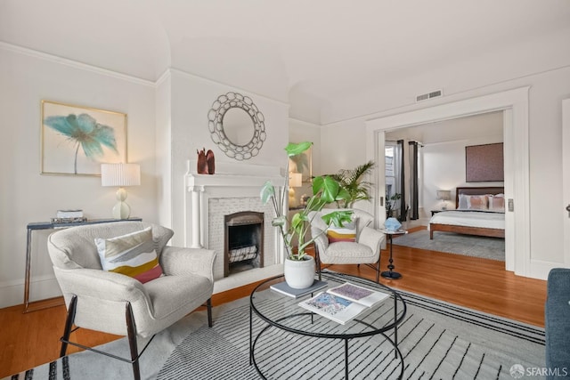 living room with a fireplace, visible vents, and wood finished floors