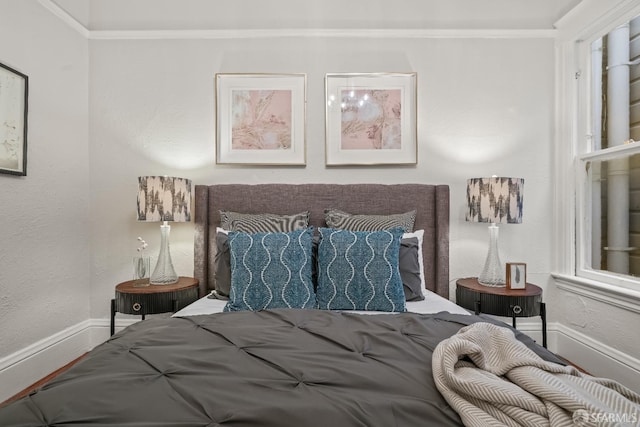 bedroom featuring crown molding, a textured wall, and baseboards