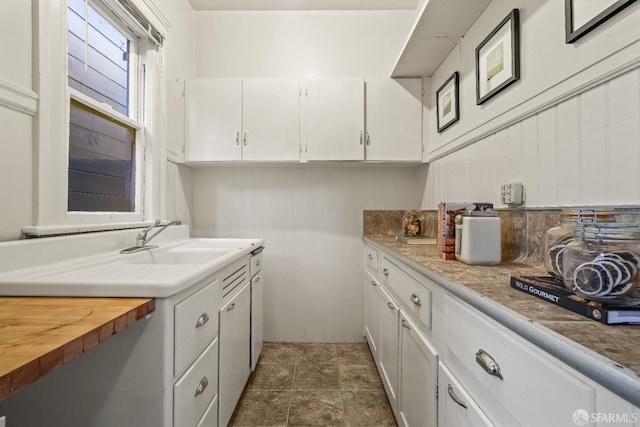 kitchen with butcher block countertops, white cabinets, and a sink