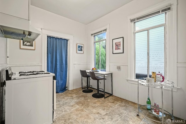 kitchen with wainscoting, white gas stove, and under cabinet range hood