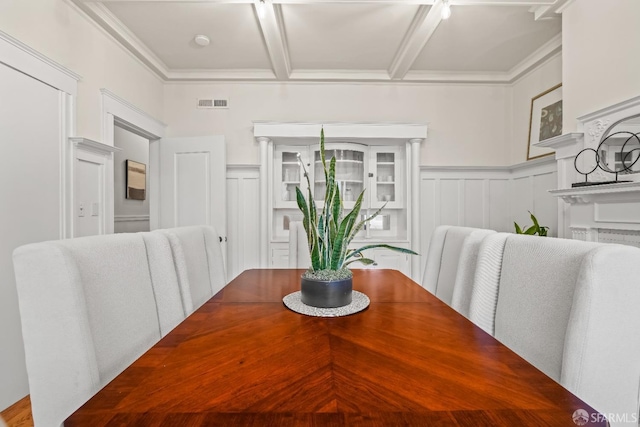 dining space with a decorative wall, visible vents, ornamental molding, and wainscoting