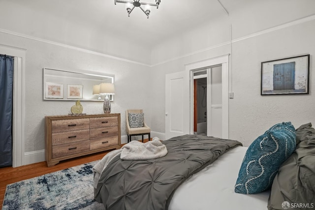 bedroom with a textured wall, wood finished floors, and baseboards