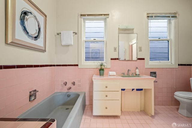 bathroom featuring tile walls, toilet, vanity, tile patterned flooring, and a bath