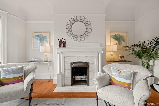 sitting room featuring ornamental molding, a fireplace, baseboards, and wood finished floors