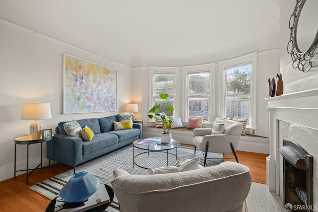 living room with a brick fireplace, baseboards, and wood finished floors