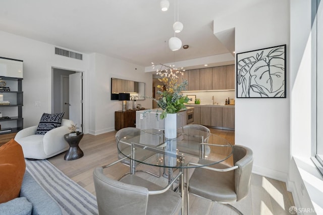 333 Beale St Unit 7G, San Francisco, CA 94105 - dining space featuring an inviting chandelier, baseboards, light wood finished floors, and visible vents
