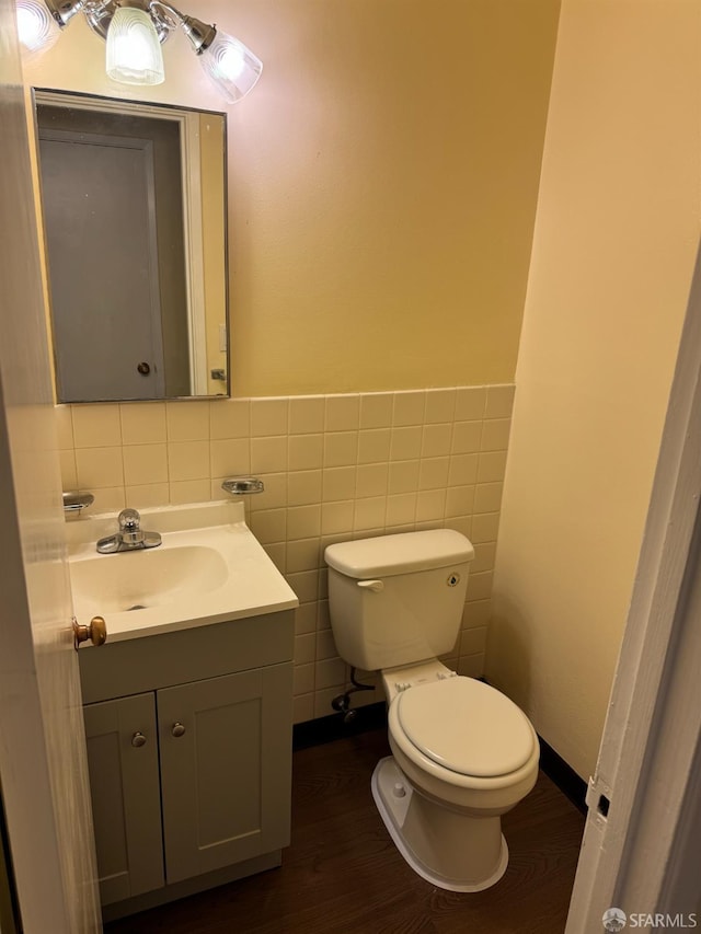 130 Albatross Ct Unit 16, San Francisco, CA 94124 - half bathroom featuring vanity, toilet, wood finished floors, tile walls, and a wainscoted wall