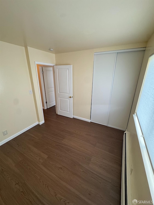 130 Albatross Ct Unit 16, San Francisco, CA 94124 - unfurnished bedroom with baseboards, dark wood-style flooring, a closet, and a baseboard heating unit