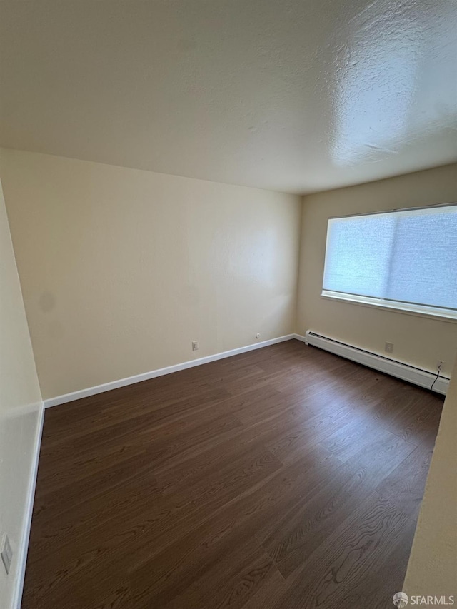130 Albatross Ct Unit 16, San Francisco, CA 94124 - spare room featuring baseboard heating, dark wood finished floors, baseboards, and a textured ceiling