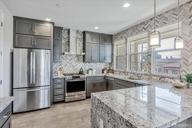 kitchen with stainless steel appliances, backsplash, a sink, wall chimney range hood, and light stone countertops