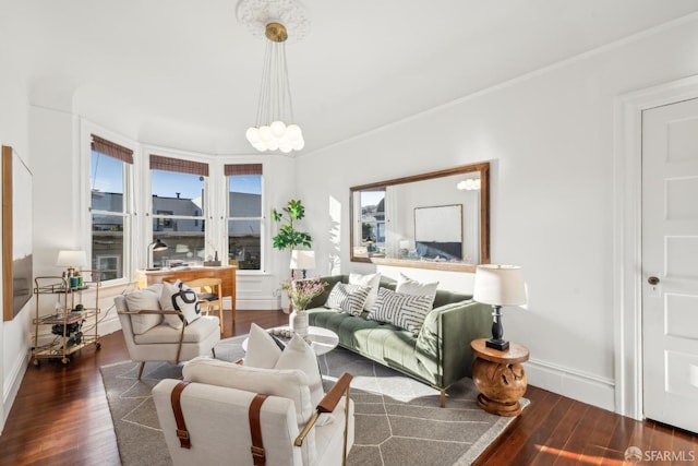 living area featuring dark wood-style floors, a chandelier, crown molding, and baseboards