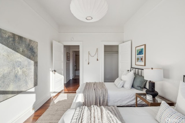 bedroom with dark wood-style floors, a closet, and baseboards