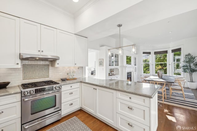 kitchen featuring decorative light fixtures, a peninsula, under cabinet range hood, white cabinetry, and stainless steel range with gas stovetop