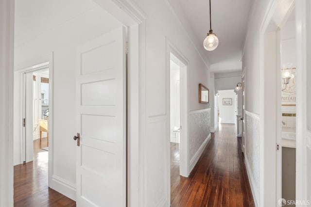 corridor with dark wood finished floors and wainscoting