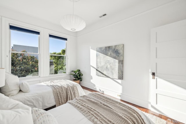 bedroom featuring visible vents, baseboards, and wood finished floors