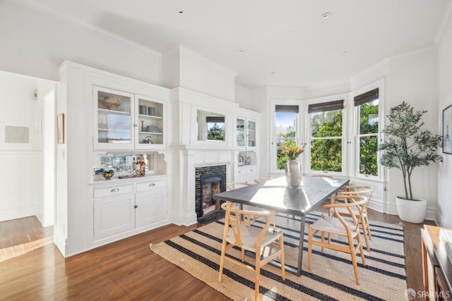 dining space featuring ornamental molding, a fireplace, and wood finished floors