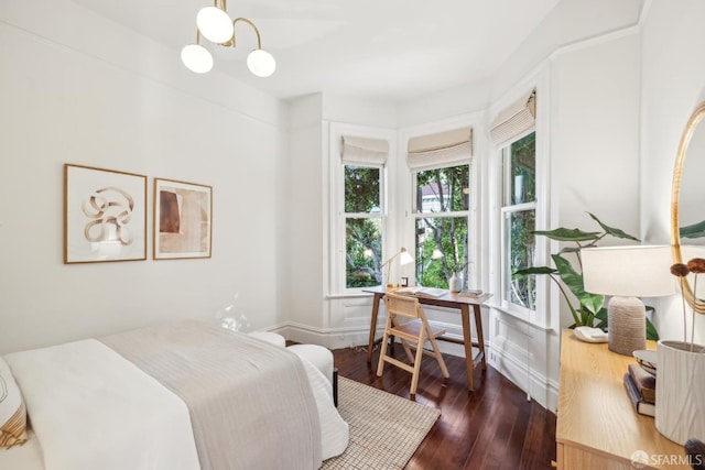 bedroom featuring an inviting chandelier and dark wood finished floors