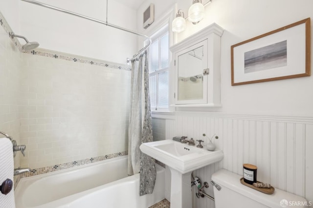 full bath featuring shower / bath combo, wainscoting, and toilet