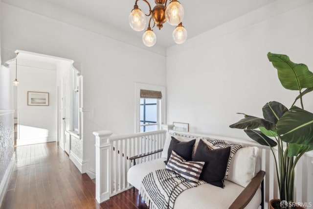 hallway with dark wood-style flooring, an upstairs landing, and an inviting chandelier