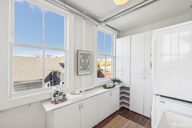 kitchen featuring stacked washer and dryer, white cabinetry, and light countertops