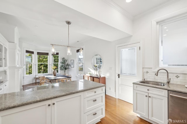 kitchen featuring light stone counters, stainless steel dishwasher, a sink, and white cabinetry