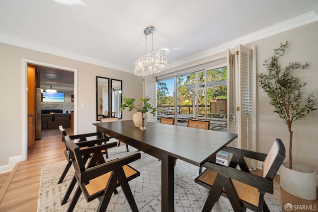 dining room with light hardwood / wood-style flooring, ornamental molding, and an inviting chandelier