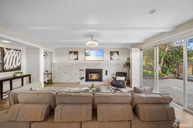 living room featuring beam ceiling and a brick fireplace