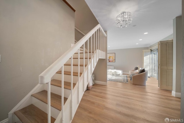 stairway with hardwood / wood-style floors and an inviting chandelier