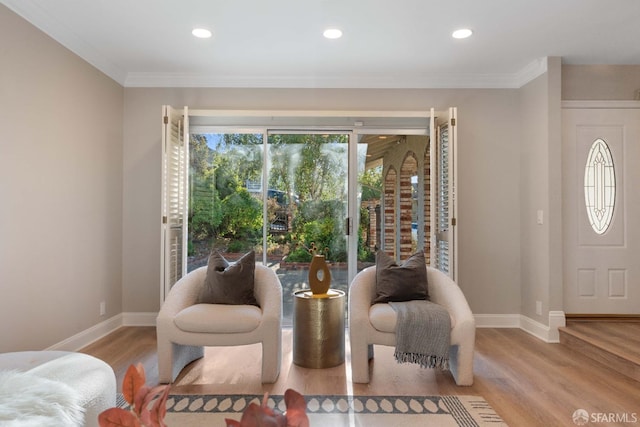 sitting room with crown molding and light wood-type flooring