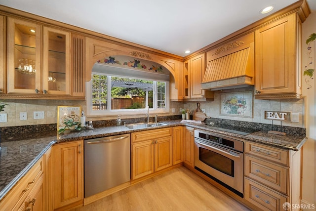 kitchen featuring dark stone counters, decorative backsplash, sink, light hardwood / wood-style flooring, and stainless steel appliances