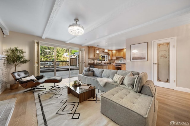 living room with light wood-type flooring, beam ceiling, and a notable chandelier