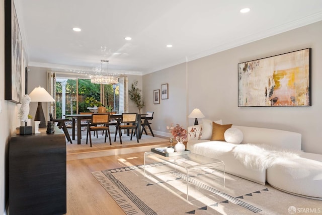 living room featuring an inviting chandelier, ornamental molding, and light wood-type flooring